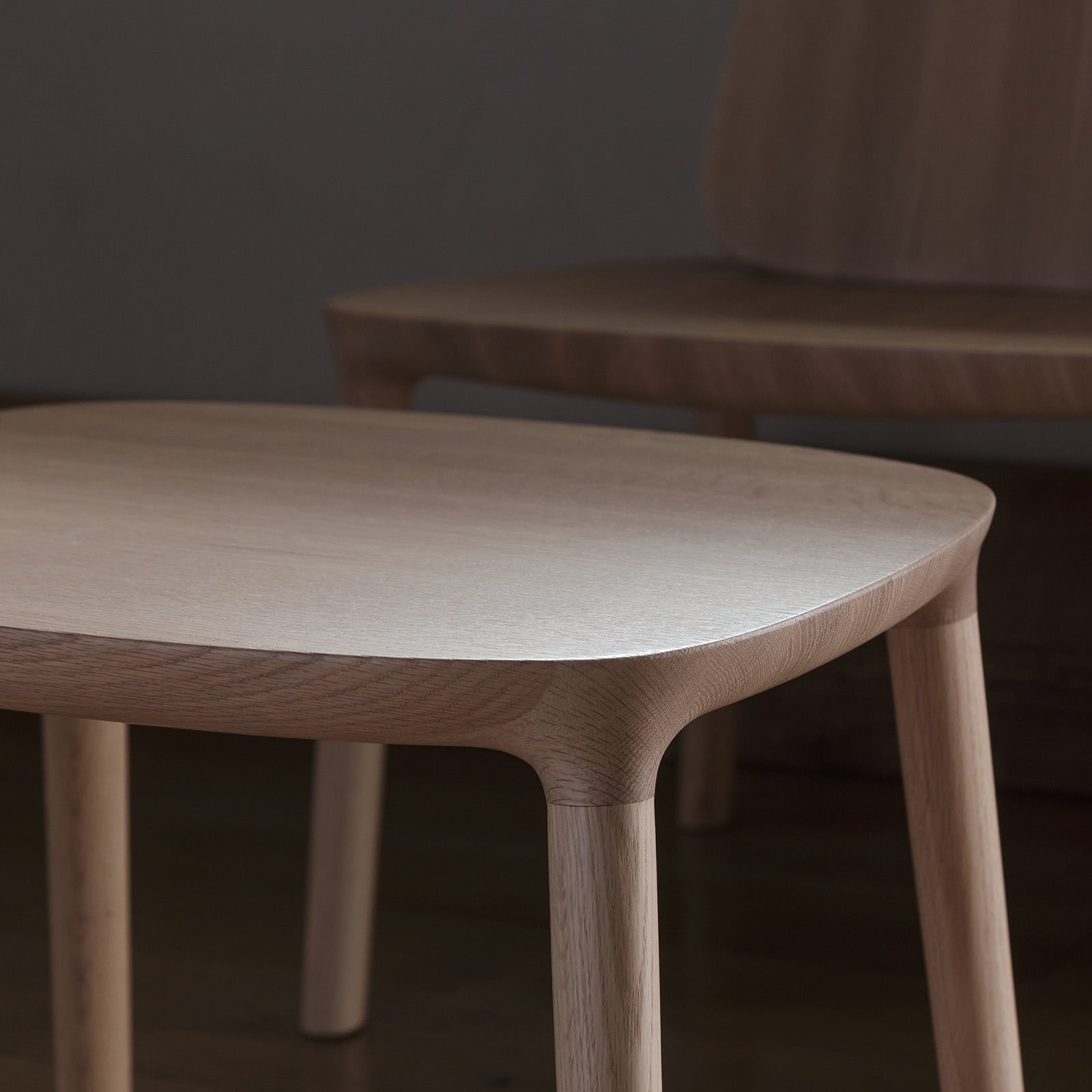 Close-up of Kokoro Ottoman in natural oak, showcasing its smooth curves and fine craftsmanship.