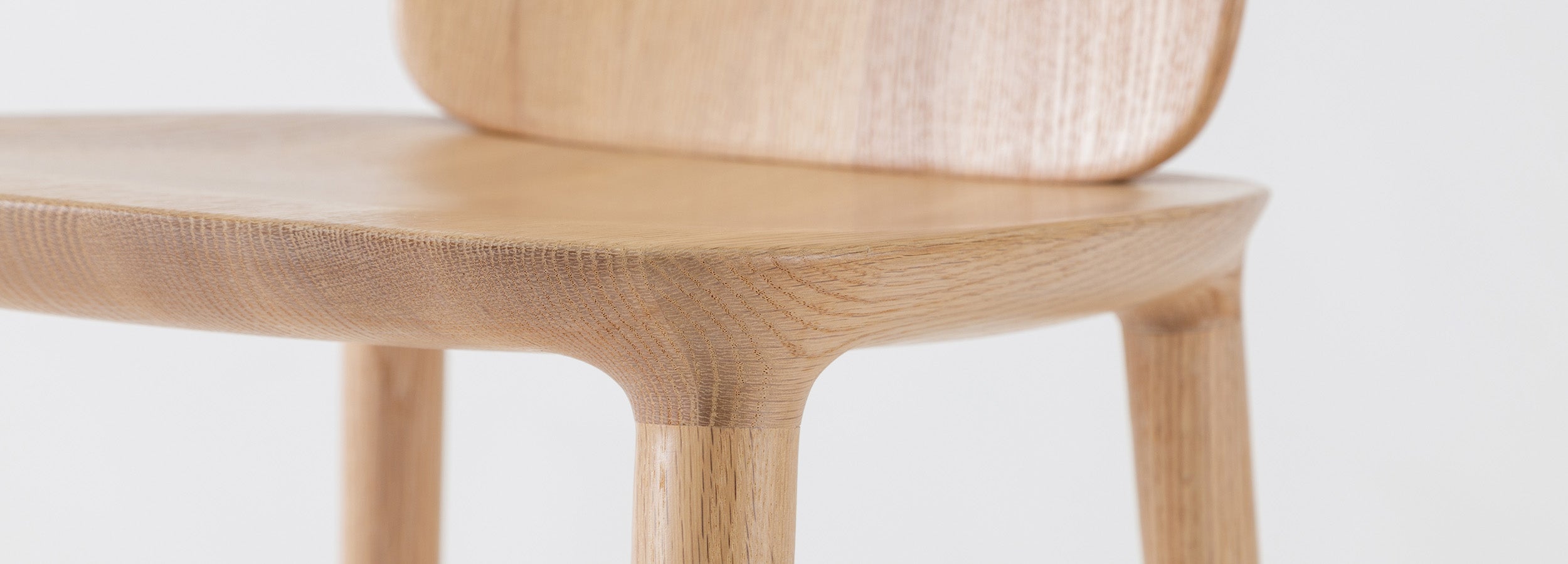 Close-up of Kokoro Dining Chair in natural oak finish, emphasizing its ergonomic design and smooth finish.