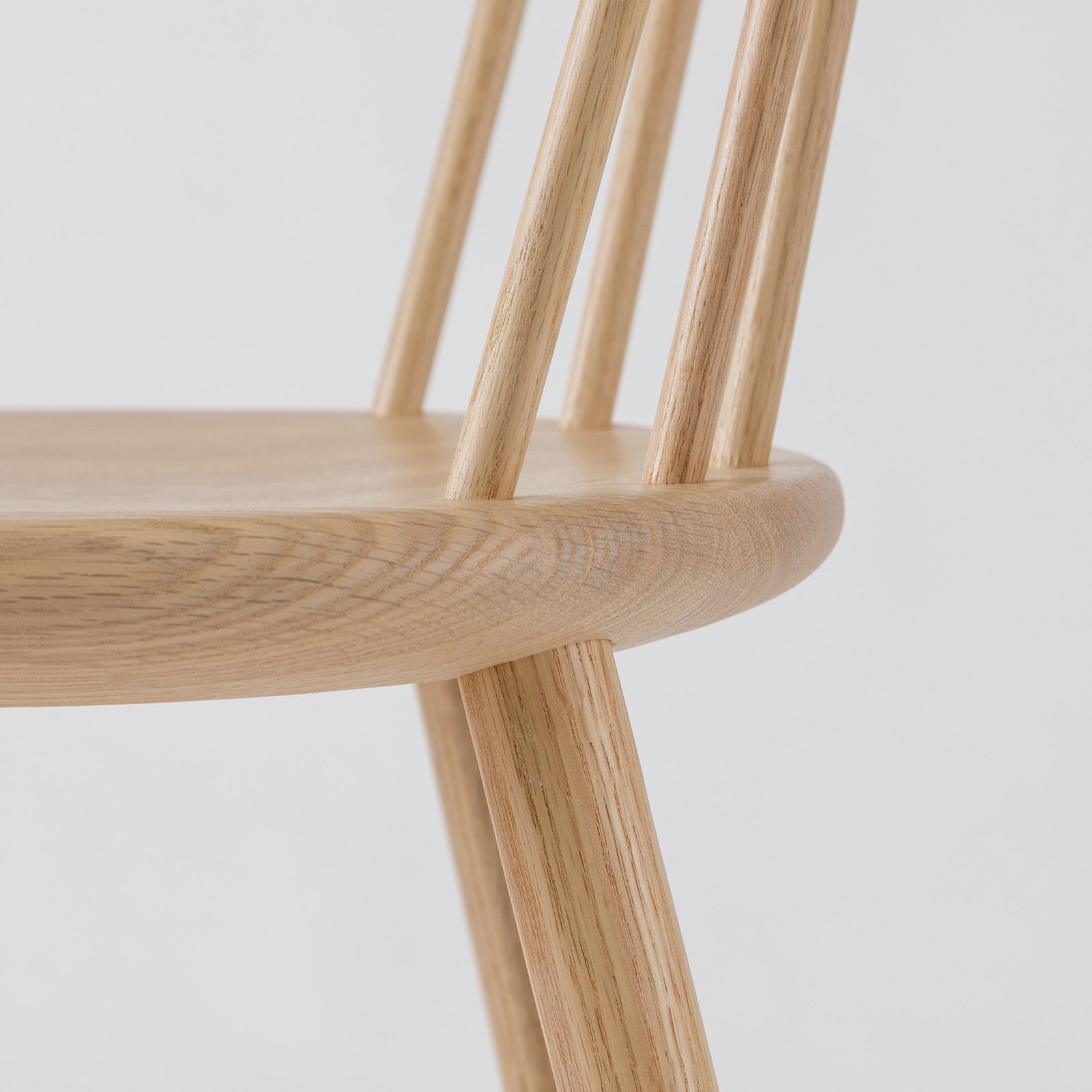 Detailed side view of the Ai Chair in natural oak, highlighting its spindled backrest and precision-crafted seat.