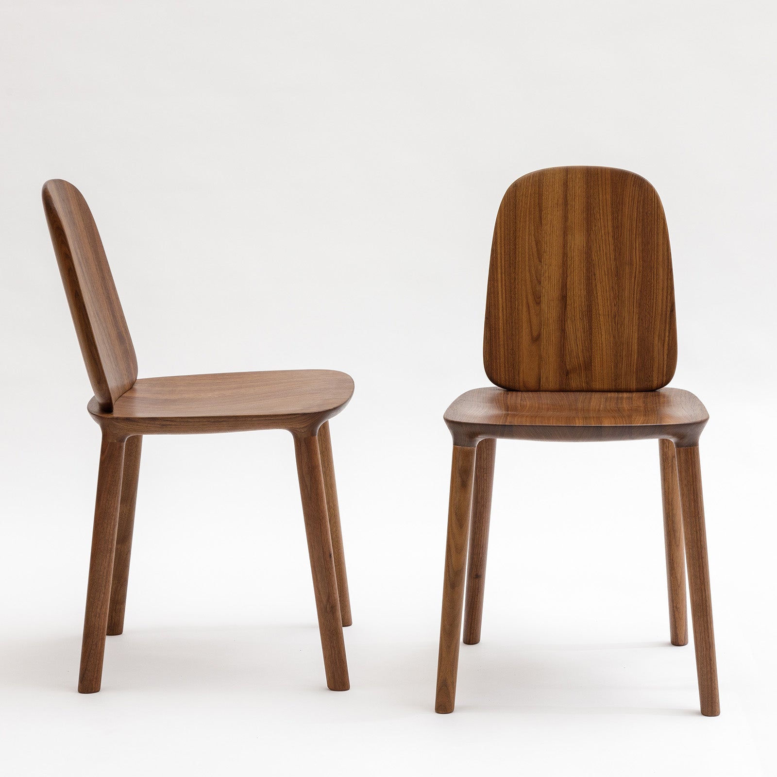 Pair of Kokoro Dining Chairs in walnut dark finish, highlighting their ergonomic backrest and sculptural design.
