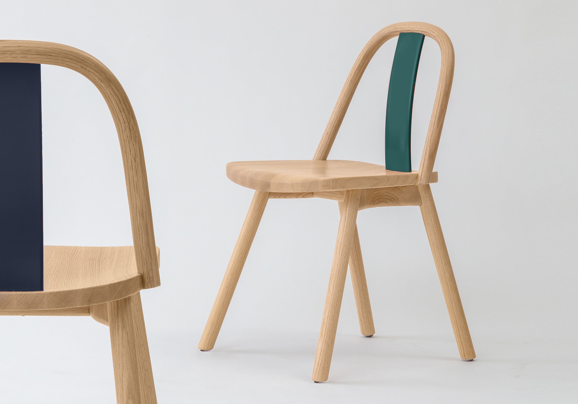 Chin-Chin chair with lacquered backrests in glossy emerald green and Black-blue, highlighting its customizable design.