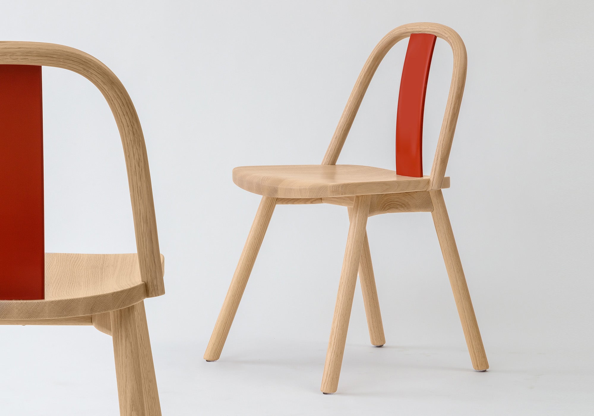 Chin-Chin chair with lacquered backrests in glossy China red and emerald green, highlighting its customizable design.