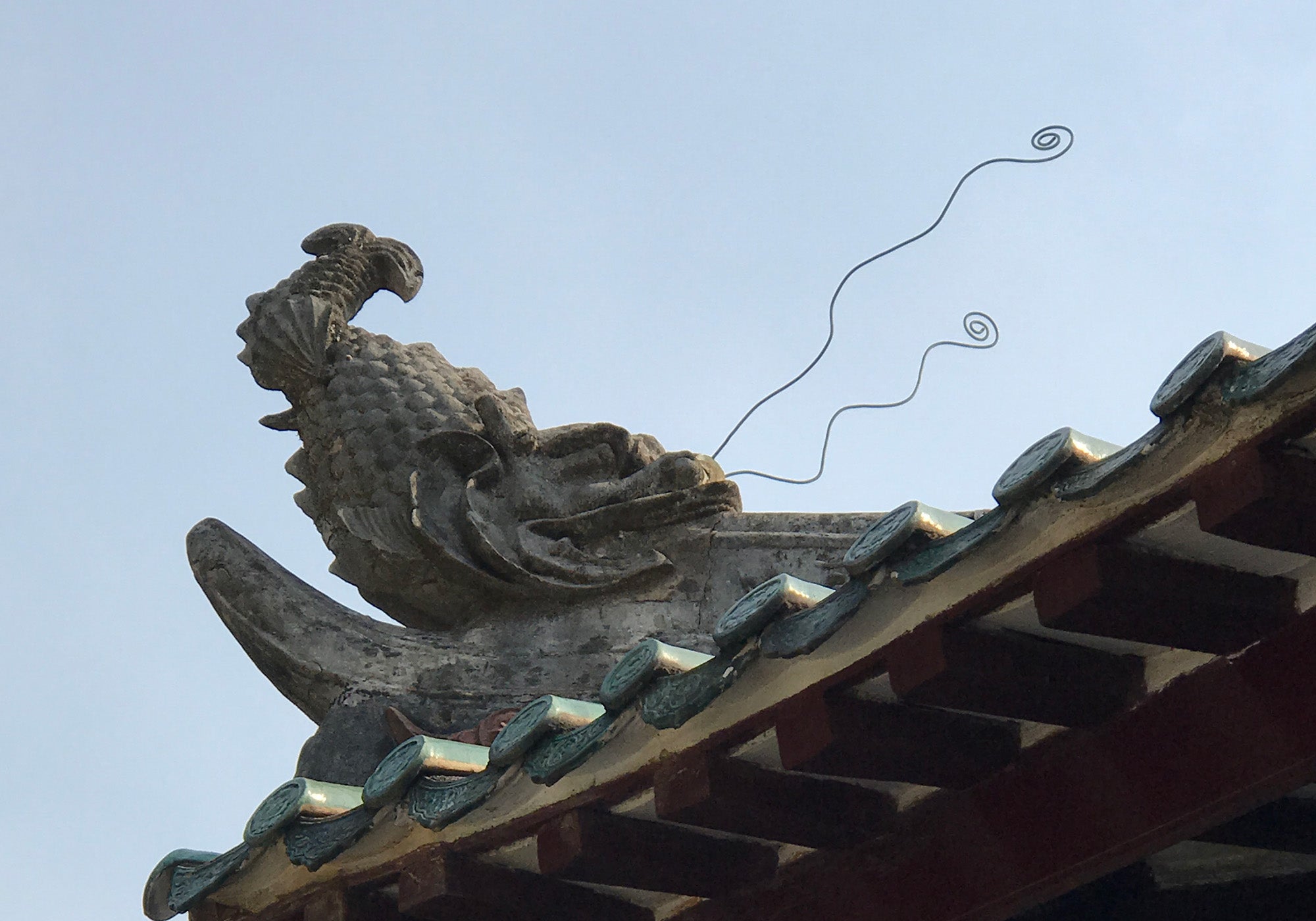 Ornamental dragon sculpture on a rooftop, symbolizing cultural heritage and architectural detail.