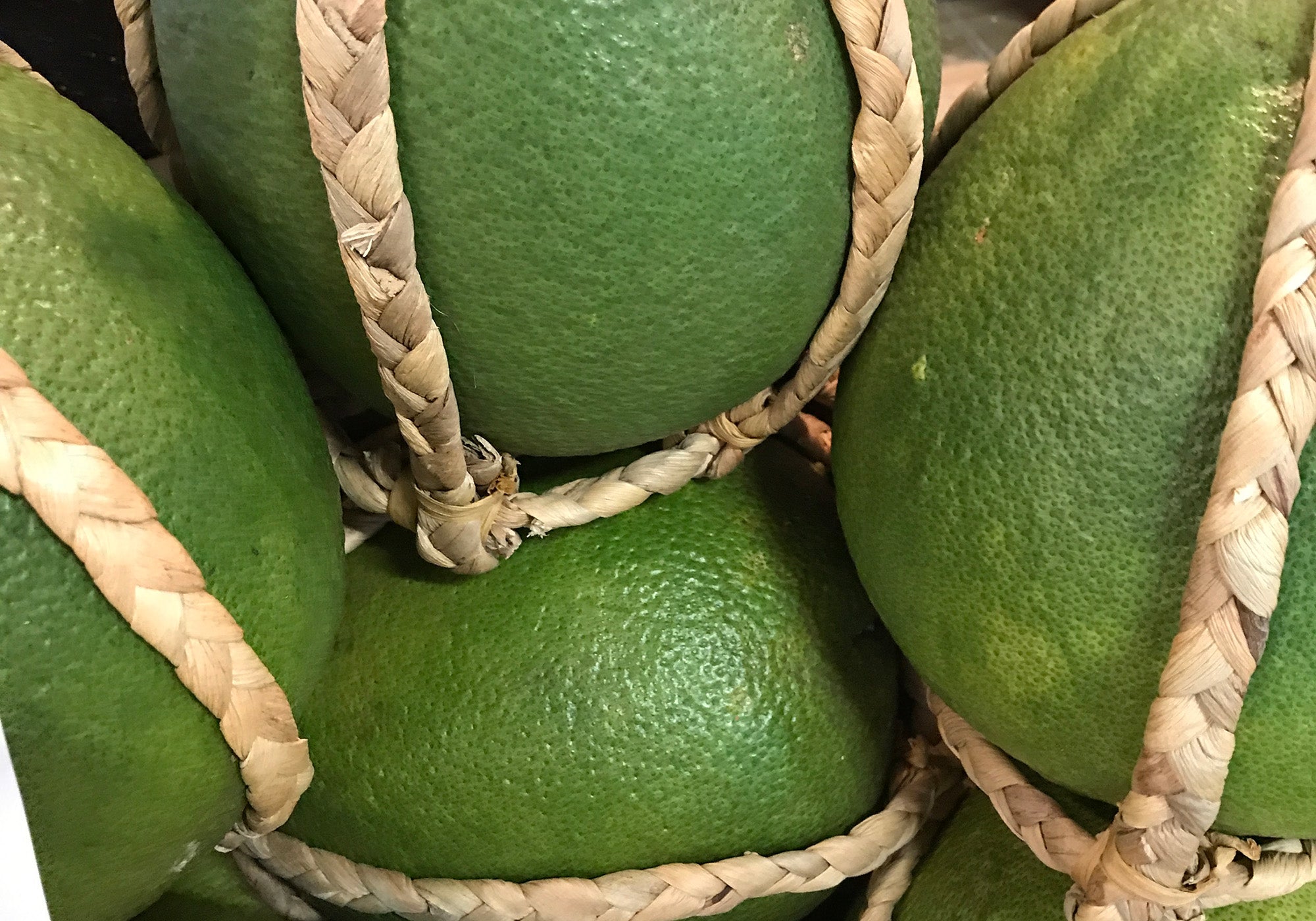 Fresh green pomelos nestled in handwoven baskets, emphasizing natural produce and artisanal packaging.