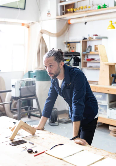 Designer Ben McCarthy in his HK workshop, working on the T&B table design.